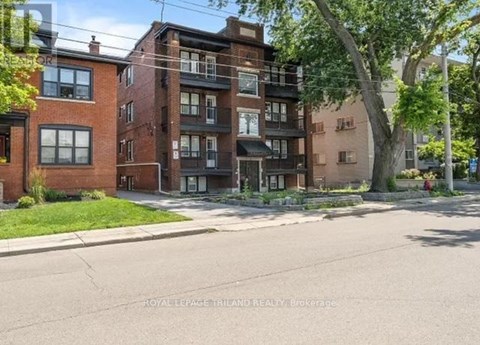 A street view of a residential area with brick buildings and a tree in the foreground.