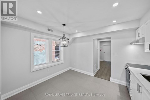 A well-lit, empty room with a chandelier and a window with blinds.