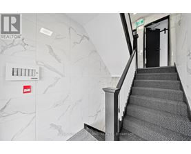 A staircase with a black carpeted runner and a white railing.