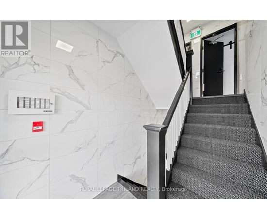 A staircase with a black carpeted runner and a white railing.