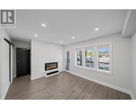 A spacious room with a fireplace and a view of the outside through the windows.