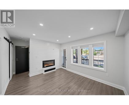 A spacious room with a fireplace and a view of the outside through the windows.