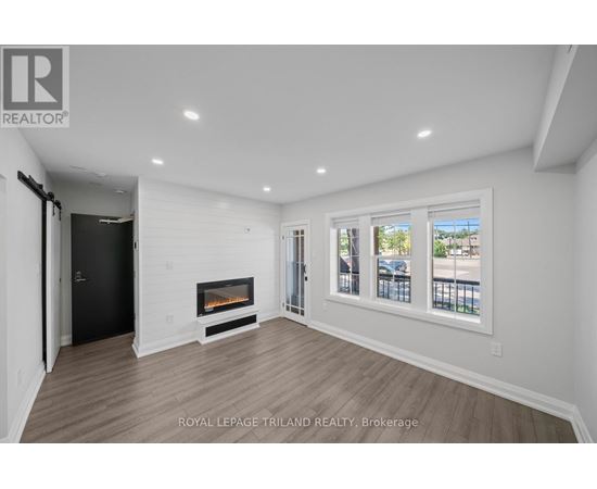 A spacious room with a fireplace and a view of the outside through the windows.