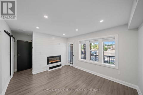 A spacious room with a fireplace and a view of the outside through the windows.