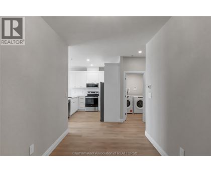 A well-lit, empty kitchen and living room with a washer and dryer in the laundry area.