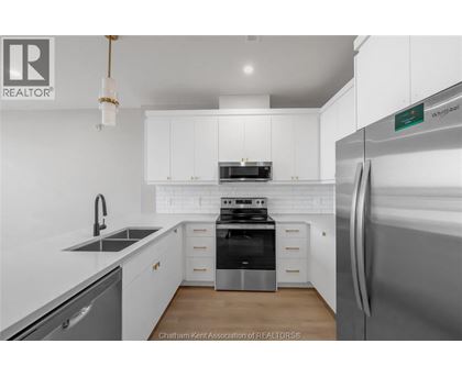 A modern kitchen with white cabinets and stainless steel appliances.