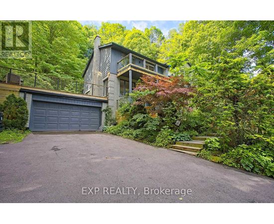 A house with a driveway and a garage is surrounded by greenery.