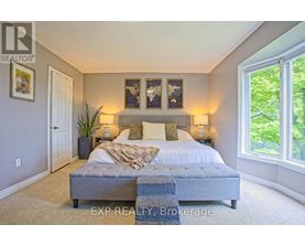 A bedroom with a large bed and a window overlooking trees.