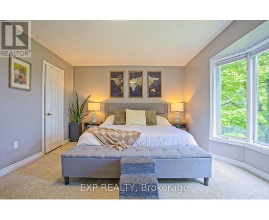 A bedroom with a large bed and a window overlooking trees.