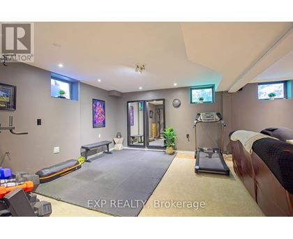 A gym room with a treadmill, exercise bench, and mirrors.