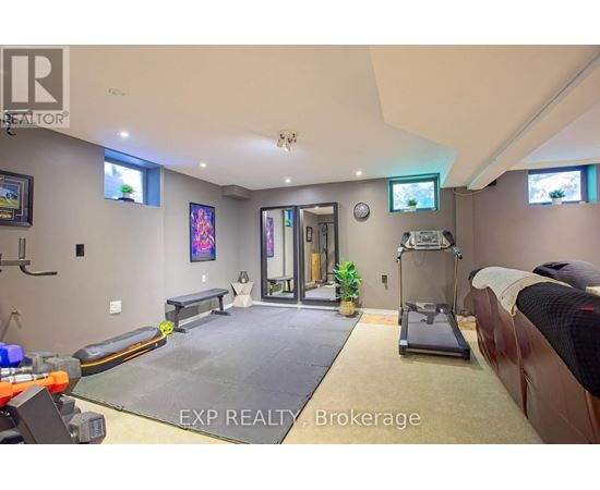 A gym room with a treadmill, exercise bench, and mirrors.