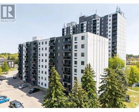 A tall residential building with a parking lot in front.