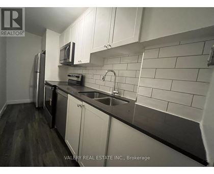 A kitchen with white cabinets and a black counter top.