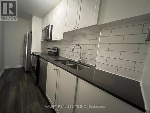 A kitchen with white cabinets and a black counter top.