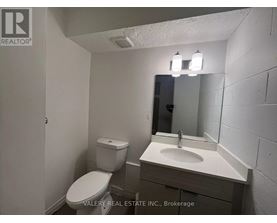 A bathroom with a toilet, sink, and mirror.