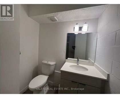 A bathroom with a toilet, sink, and mirror.