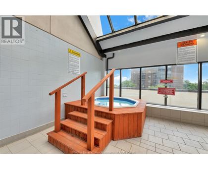 A hot tub is in a room with a skylight.