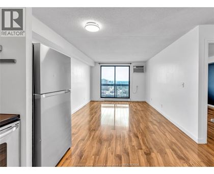A spacious kitchen with wooden floors and a refrigerator.