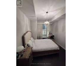 A bedroom with a bed, nightstand, and a chandelier.