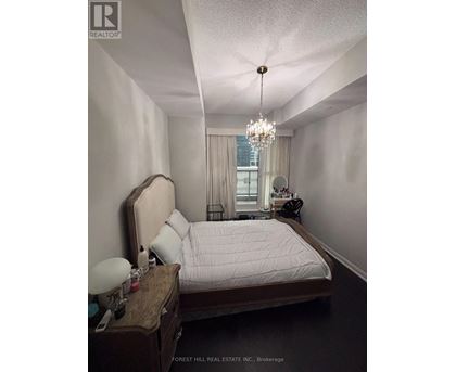 A bedroom with a bed, nightstand, and a chandelier.