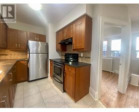 A kitchen with wooden cabinets and a stainless steel refrigerator.