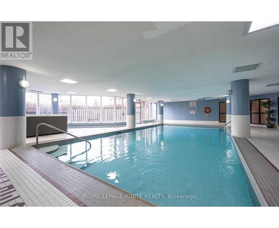 A swimming pool inside a building with a bench and a diving board.