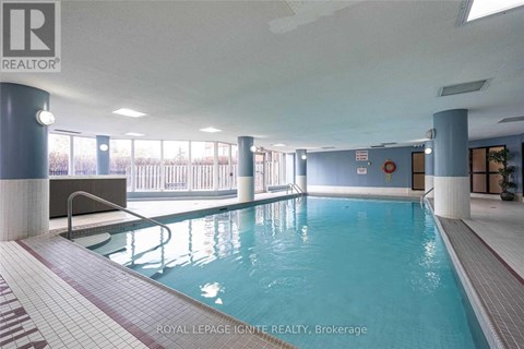 A swimming pool inside a building with a bench and a diving board.