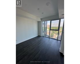 A spacious room with a view of the cityscape through large windows.