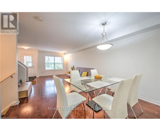 A dining room with a glass table and white chairs.