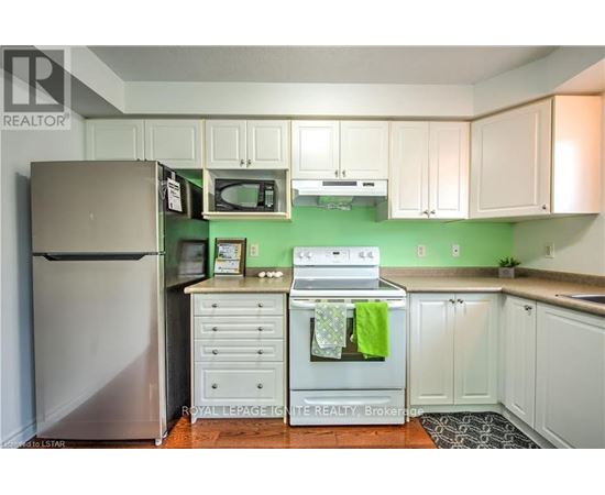 A kitchen with white cabinets and green walls.