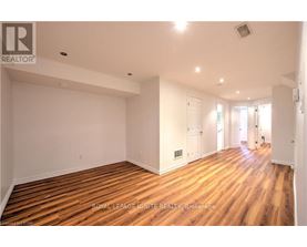 A spacious room with wooden flooring and white walls.