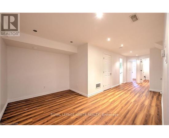 A spacious room with wooden flooring and white walls.