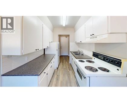 A white kitchen with a stove top oven and cabinets.