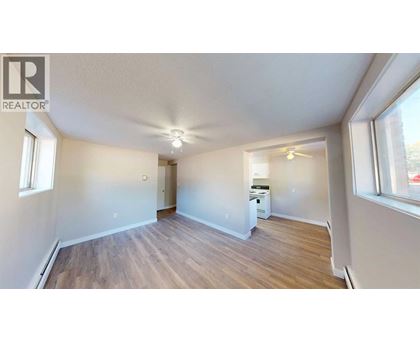 A spacious room with wooden flooring and a ceiling fan.