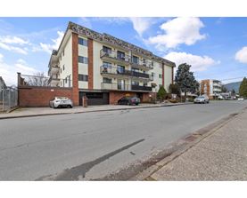 A street view of a residential area with apartment buildings and cars parked on the side of the road.