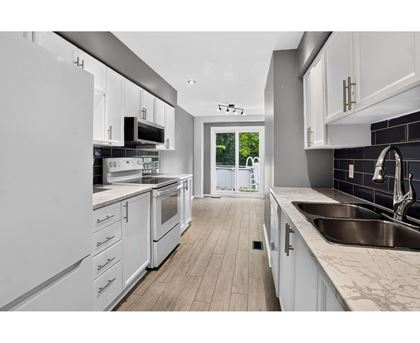 A modern kitchen with white cabinets and stainless steel appliances.
