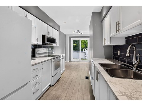 A modern kitchen with white cabinets and stainless steel appliances.