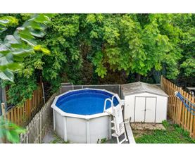 A small above ground pool surrounded by a wooden fence and trees.