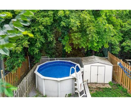 A small above ground pool surrounded by a wooden fence and trees.