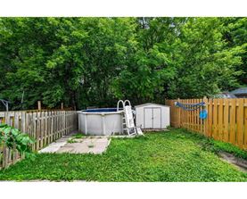 A backyard with a hot tub, a chair, and a shed.