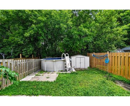 A backyard with a hot tub, a chair, and a shed.