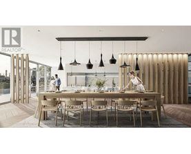 A modern dining area with a long table and chairs, and pendant lights hanging above.