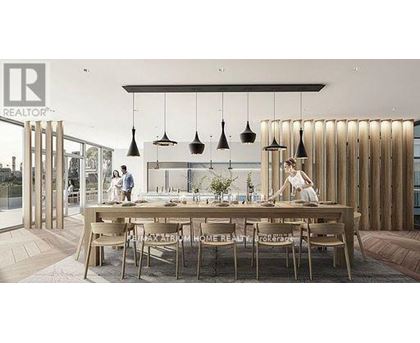 A modern dining area with a long table and chairs, and pendant lights hanging above.