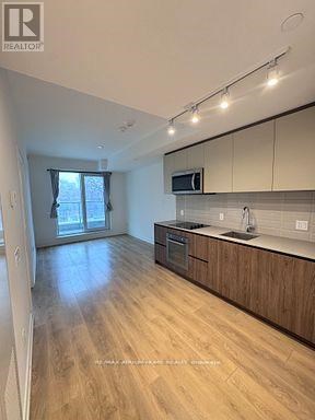 A kitchen with wooden floors and a microwave above the stove.