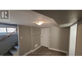 A room with a white door and a staircase with a wooden handrail.