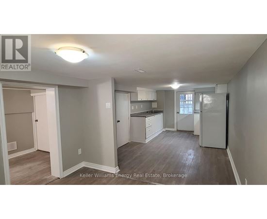 A well-lit, spacious kitchen and living room area with a refrigerator, sink, and cabinets.
