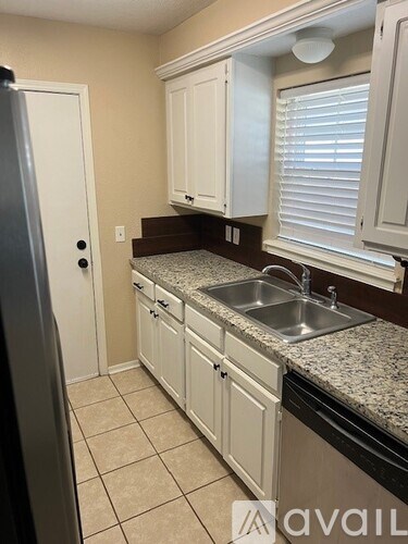A kitchen with white cabinets and a granite countertop.