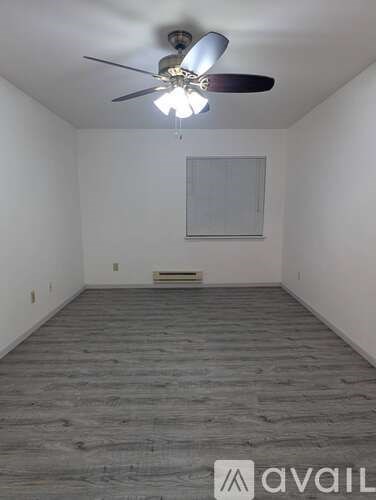 A room with a ceiling fan and wooden flooring.