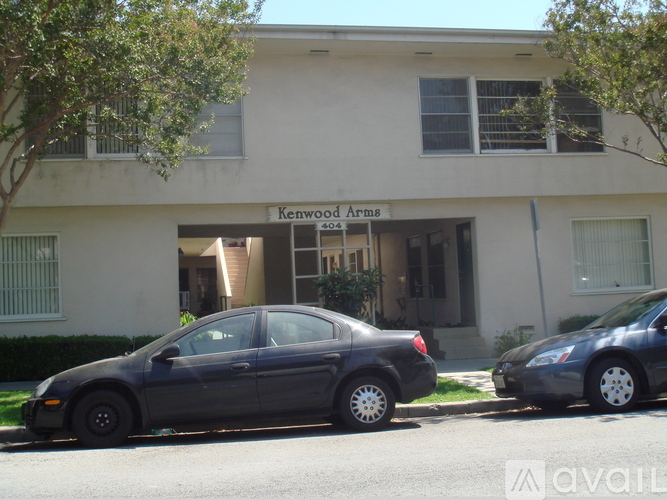 A black car is parked in front of a building with the sign "Kenwood Arms.".