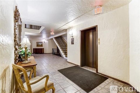 A hallway with a wooden chair and a rug on the floor.